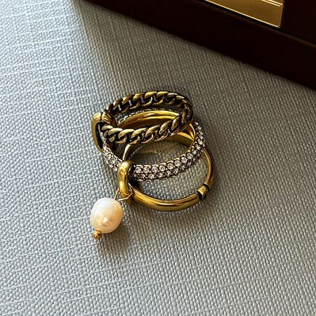 Wholesale Brass Rings Collection - A stylish collection of wholesale brass rings from JR Fashion Accessories, featuring a set of three gold-toned rings with a delicate pearl pendant.