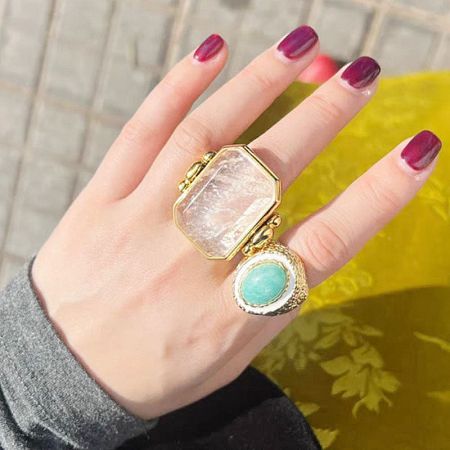 Two gold statement rings from the set, one with a white stone and another with a turquoise-like stone.