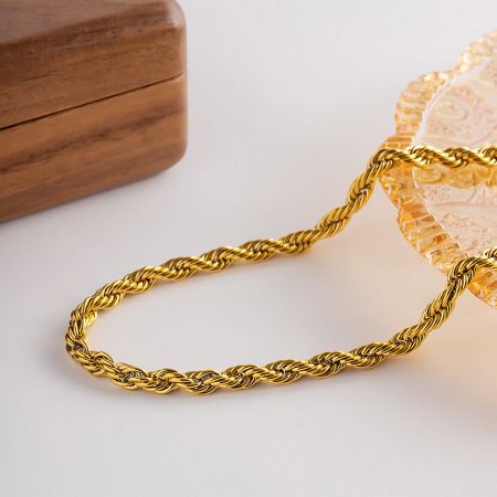 Lifestyle image of the gold rope chain necklace elegantly displayed in a glass dish.