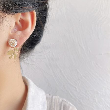 Close-up view of a single 3D white rose stud earring, highlighting the intricate gold-plated leaf details.