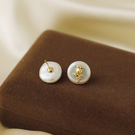Close-up shot of the white earrings with a detailed gold rose design.