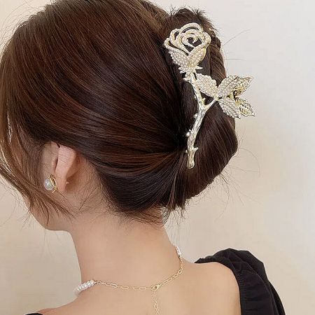Detailed close-up of a gold rose hair clip featuring pearl and rhinestone accents.