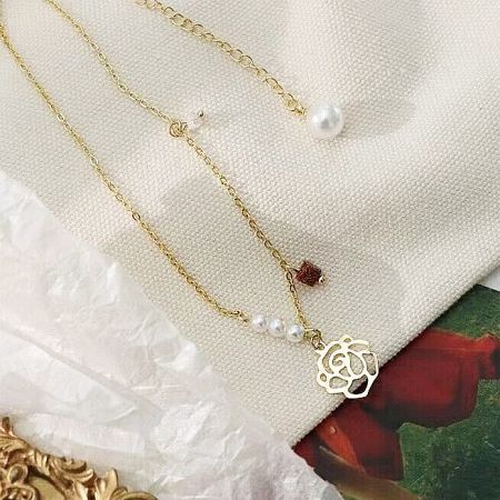 Primo piano del pendente a forma di rosa vuota sulla collana choker placcata in oro.