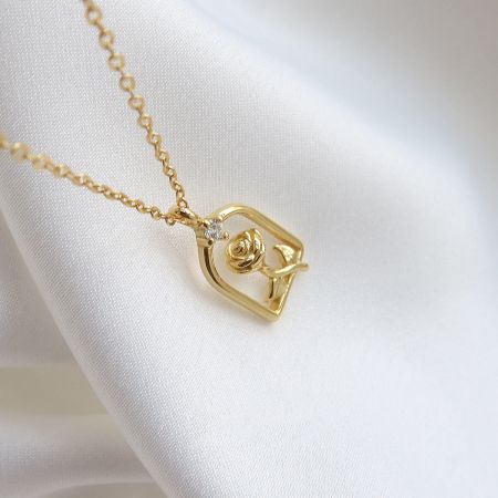 The gold version of the rose pendant necklace, featuring a square frame and diamond accent.