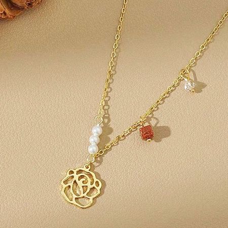 Una collana d'oro del set con pendente a forma di rosa e vari charm delicati.