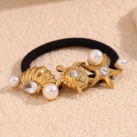 Close-up of the gold starfish and turtle charms with pearl details on the stainless steel hair tie.
