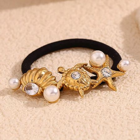 Close-up of a luxurious gold sea-themed hair tie decorated with pearls, gemstones, a seashell, and a starfish.