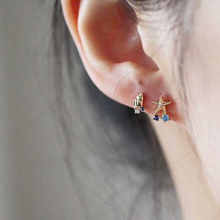 A pair of mismatched ocean-themed earrings: a seahorse and a starfish, both with blue gems.