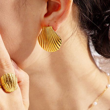 Model showcasing the shell earring paired with a matching gold ring.