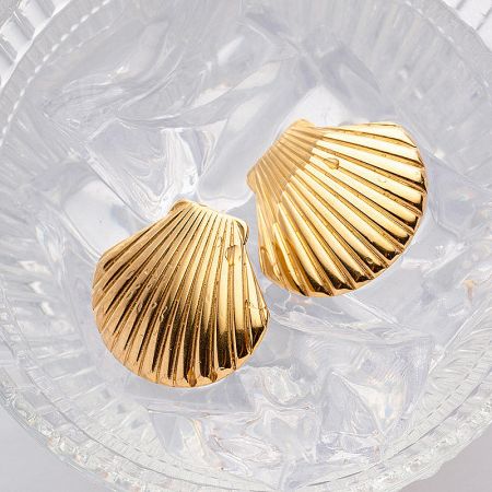 The set of gold shell earrings elegantly displayed in a clear glass dish.