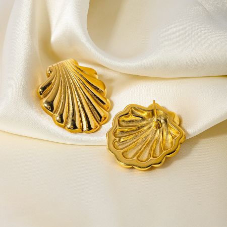 A pair of gold scallop shell stud earrings displayed elegantly on a white satin background.
