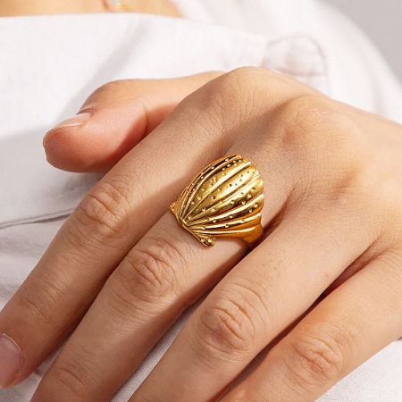 An alternative angle of the gold seashell ring worn on a finger.