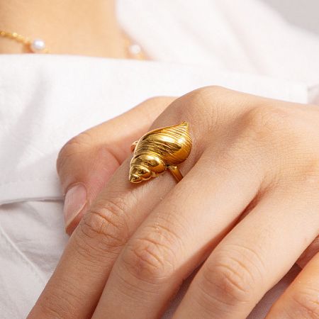 Close-up of the gold seashell ring on a model's finger.