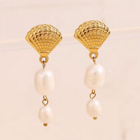 Detailed view of the gold shell pearl drop earrings, highlighting the textured grid pattern and two baroque pearls.