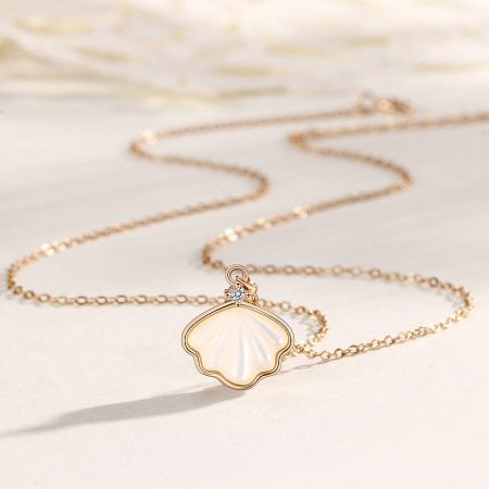 Close-up of the gold-plated sea shell pendant, revealing its intricate details and sparkling accent.