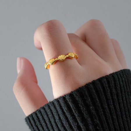Gold-plated seashell ring worn on a finger.