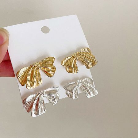 Close-up of the metallic bowknot stud earrings on a display card.