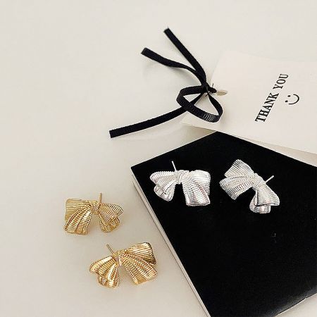 Complete product view including the bow-shaped earrings and their packaging.