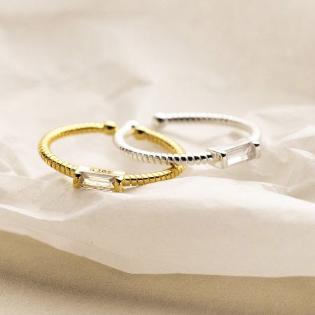 Top-down view of the gold and silver sterling silver rings with sparkling rectangular crystals.