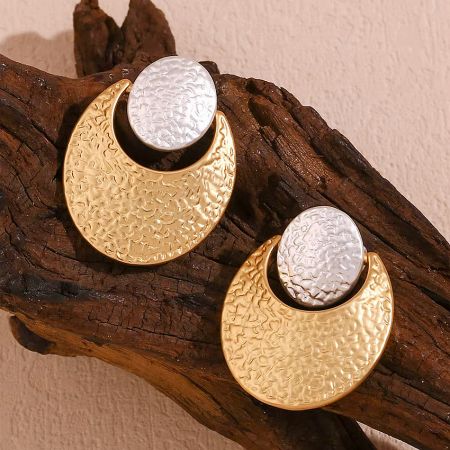 Two-tone crescent moon earrings elegantly displayed on natural driftwood.