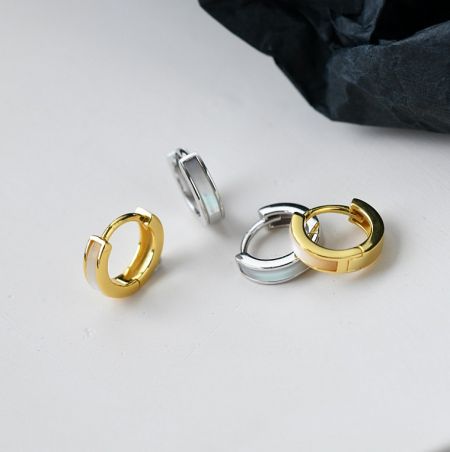 925 Sterling Zilveren Schelp Huggie Oorbellen - De afbeelding toont oorbellen in goud en zilver, waarschijnlijk voor promotionele of verkoopdoeleinden.