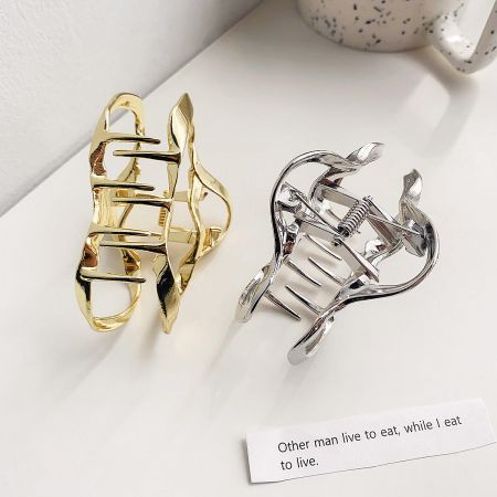 Two metal hair clips, one gold and one silver, with a unique wavy design.