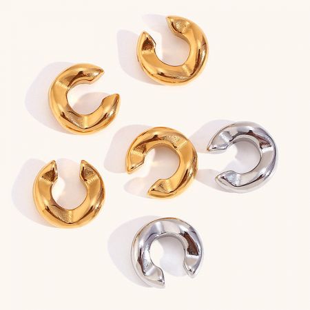 A collection of gold and silver stainless steel ear cuff earrings shown together.