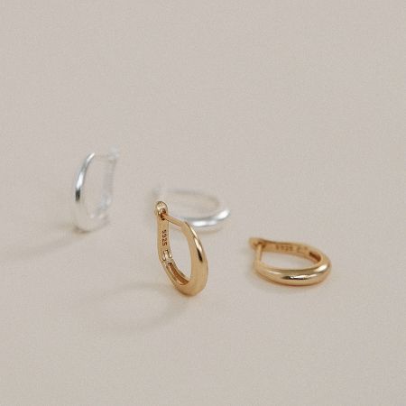A set of teardrop-designed hoop earrings in both gold and silver finishes, displayed on a neutral background.