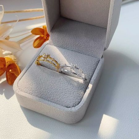 Gold and silver versions of the adjustable butterfly ring displayed in a gray jewelry box.