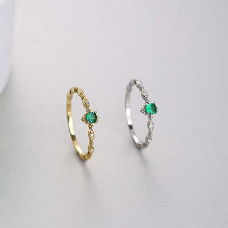 Detailed view of the intricate bands on the gold and silver emerald zircon rings.