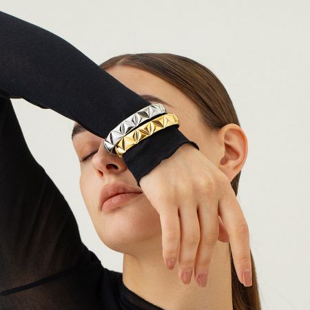 A model showcasing the layered look of the gold and silver textured cuff bracelets.