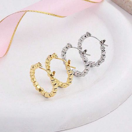 A pair of gold and a pair of silver textured hoop earrings displayed side-by-side.