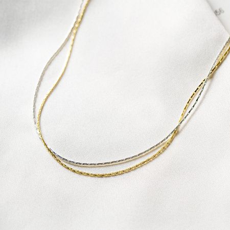 Detailed view of the intertwined gold and silver snake chain necklaces, emphasizing the quality craftsmanship.