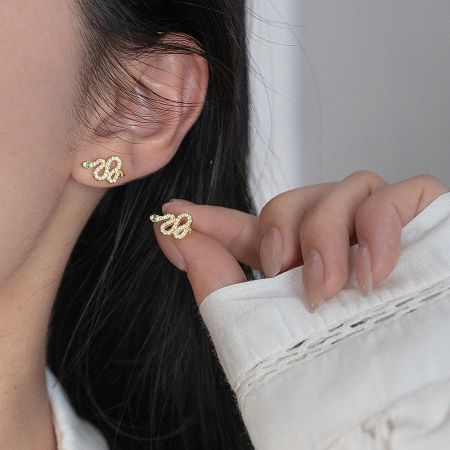 Close-up of the gold-plated version of the snake stud earrings with sparkling stones.