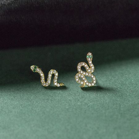 Elegant gold snake earrings adorned with white stones and vibrant green gemstone eyes.