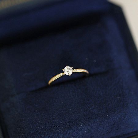 The elegant solitaire ring presented in a luxurious dark blue velvet box, perfect for gifting or retail display.
