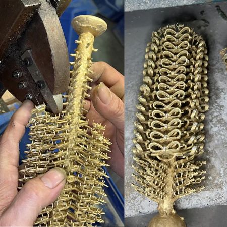 An intricately cast gold decorative piece with a spine-like structure.