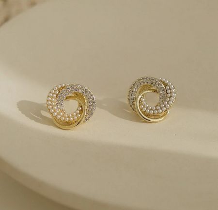 Elegant gold spiral earrings with pearls and gemstones, showcasing alternative styles.