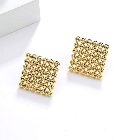 Detailed view of the square stud earrings with a textured grid pattern of small spheres.