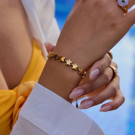 Close-up of the stainless steel gold star bracelet on a woman's hand.