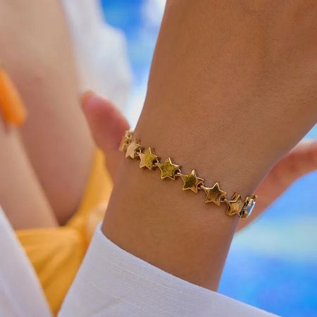 A woman wearing the adjustable gold star bracelet on her wrist.