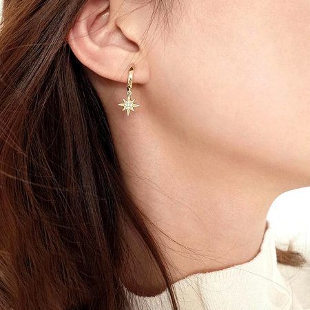 A model showcasing the delicate gold star charm earring.