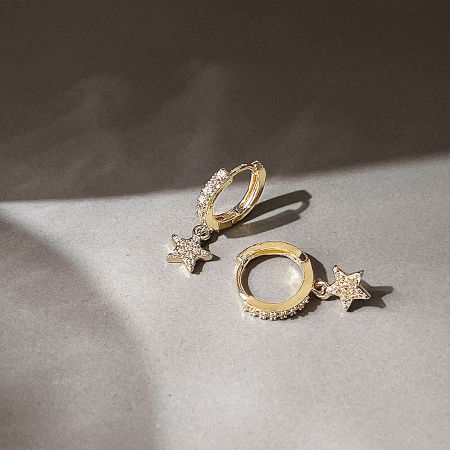 Angled shot of the pair of gold star huggie hoop earrings, showing their shine and craftsmanship.