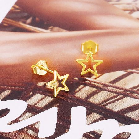 Detailed studio shot of the pair of gold-finished 925 sterling silver hollow-out star stud earrings.