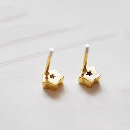 A pair of classic gold star-shaped stud earrings on a white background.