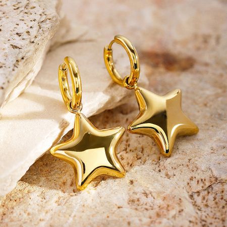 Detailed shot of the gold star dangle huggie earrings.