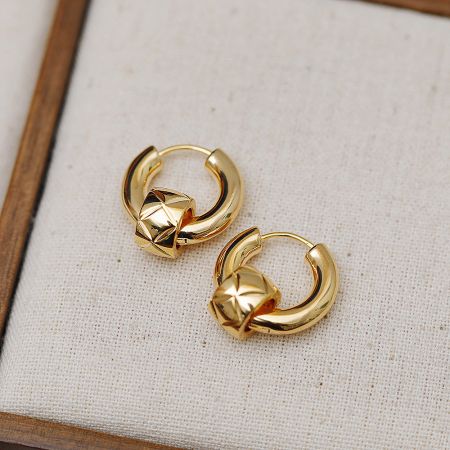 Gold huggie earrings with a star-shaped design.