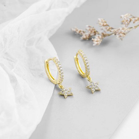 A detailed shot of the gold star hoop earrings, emphasizing the sparkle of the clear pavé stones.