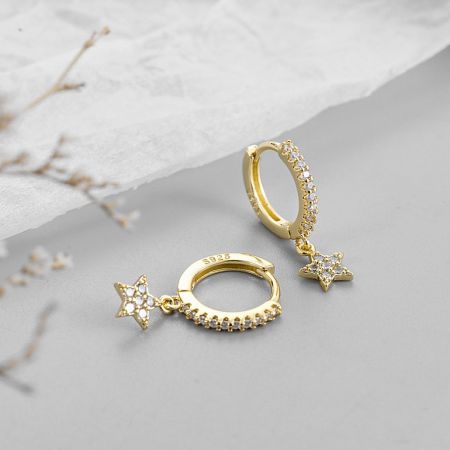 Side view of the gold celestial huggie hoop earrings showcasing the clear gemstones on the star charm.