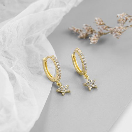 Detailed shot of the celestial star huggie hoop earring, highlighting the white gemstones.